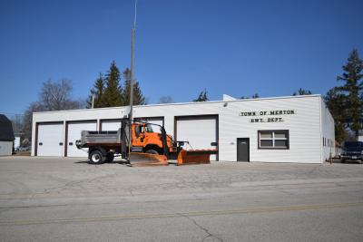 Orange plow truck in front of the Town of Merton Highway Garage